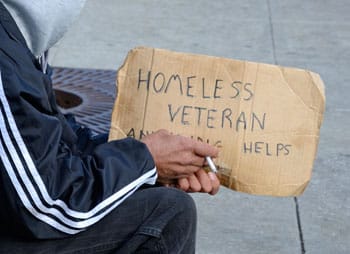 hands of person holding sign that reads "homeless veteran need help"